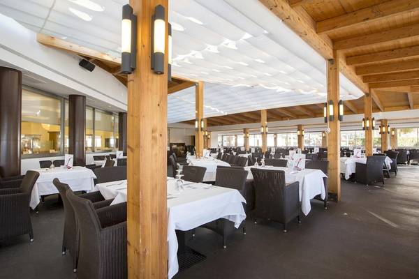 Innenansicht des Restaurants im Hipotels Cala Millor Park mit gedeckten Tischen und Holzstützen.