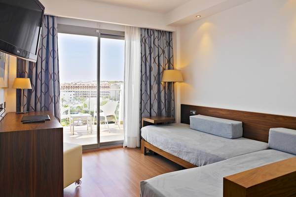 Innenansicht eines Zimmers im Hipotels Cala Millor Park mit zwei Betten, Schreibtisch, Fernseher und Balkon.