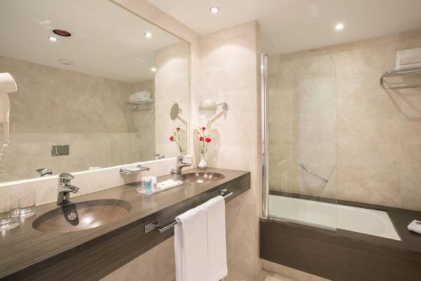 Ein elegantes Badezimmer im Hipotels Cala Millor Park mit zwei Waschbecken, einem Spiegel und einer Dusche.