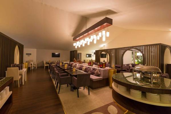 Innenansicht des Restaurants im St. Regis Saadiyat Island Resort mit Tischen, Stühlen und einer langen Bank.