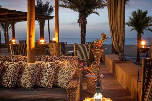 Loungebereich im St. Regis Saadiyat Island Resort mit Blick auf den Ozean und Palmen.