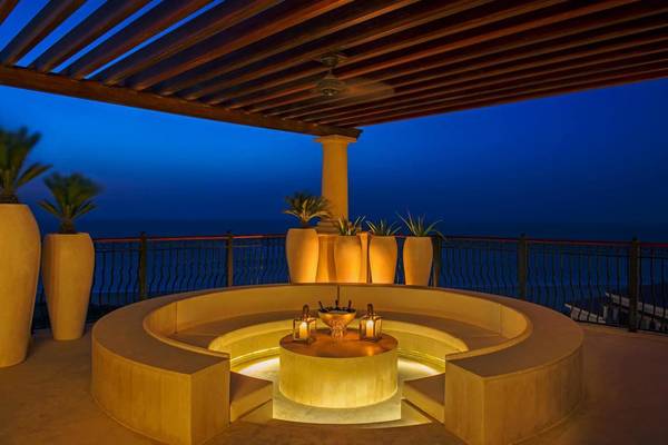 Terrasse des St. Regis Saadiyat Island Resort mit Blick auf den Ozean und beleuchteten Pflanzen.