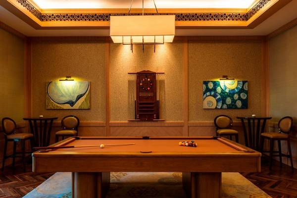 Pooltisch im Spielzimmer des St. Regis Saadiyat Island Resort mit zwei Kunstwerken an der Wand und runden Stühlen