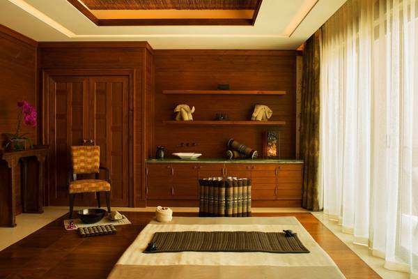 Innenansicht eines Massageraums im St. Regis Saadiyat Island Resort mit Holzmöbeln und Dekogegenständen.
