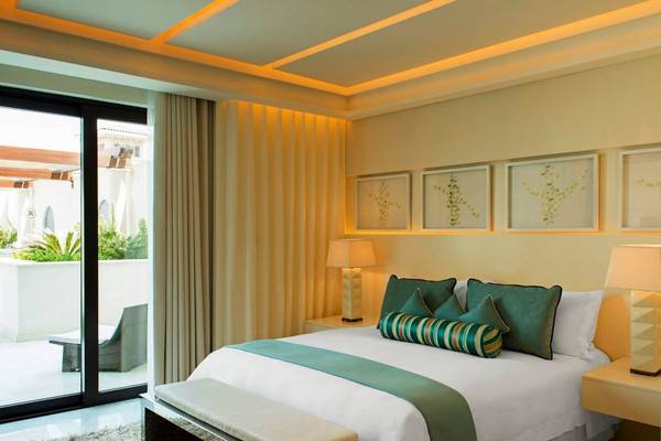Schlafzimmer im St. Regis Saadiyat Island Resort mit einem großen Bett, grünen Kissen und einem offenen Balkon.
