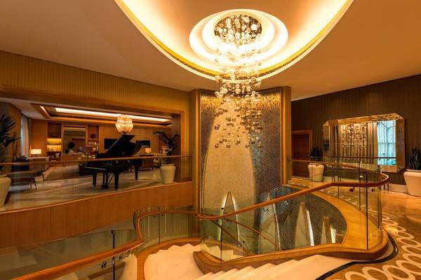 Empfangsbereich im St. Regis Saadiyat Island Resort mit einer Wendeltreppe und einem großen Kristallleuchter.