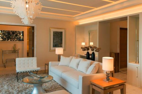 Wohnzimmer im St. Regis Saadiyat Island Resort mit weißer Couch, Lampen und Teppich.