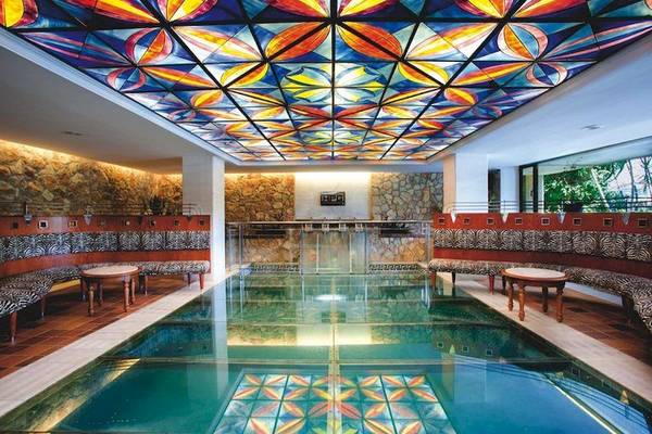 Innenpool des Playa Golf Hotels mit bunter Glasdecke und Zebramuster-Bänken