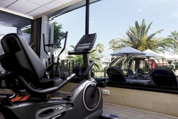 Fitnessbereich im Playa Golf Hotel mit Blick auf Palmen und Sonnenschirme
