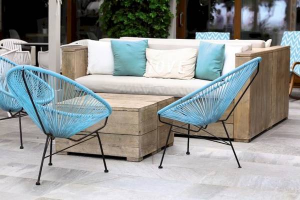 Eine Holzcouch mit blauen Sesseln auf einer Terrasse des Playa Golf Hotels.