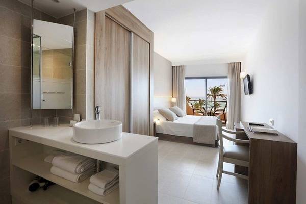 Innenansicht eines Zimmers im Playa Golf Hotel mit Bett, Schreibtisch, Stuhl, Spiegel und Badezimmer.