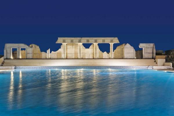Nachtansicht des Kipriotis Village Resorts mit einem großen Pool und einer antiken Tempelarchitektur im Hintergrund.