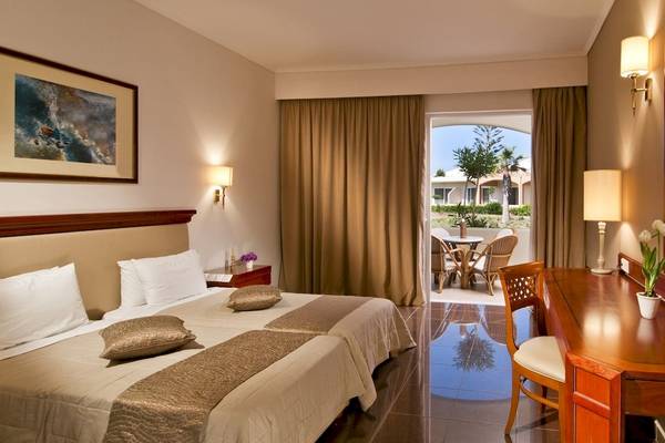 Hotelzimmer im Kipriotis Village Resort mit zwei Betten, Tisch, Stuhl und Balkon.