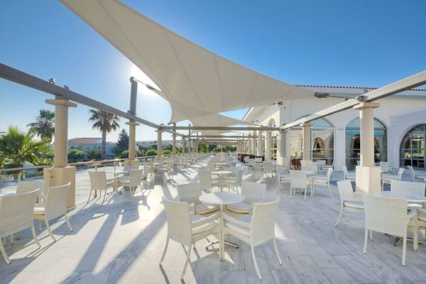 Außenbereich des Kipriotis Village Resort mit vielen weißen Tischen und Stühlen.