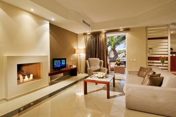 Wohnzimmer im Kipriotis Village Resort mit Fernseher, Kamin und Sofa.