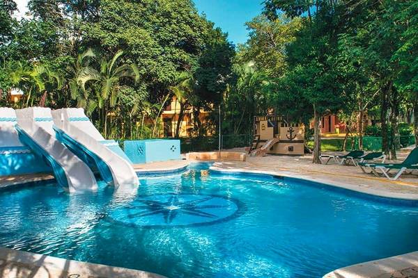Pool des Riu Lupita Hotels mit Rutschen und Liegen vor tropischer Kulisse