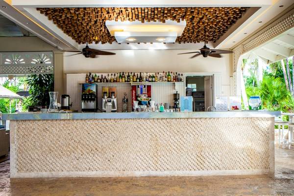 Innenansicht der Bar im Vista Sol Punta Cana Beach Resort & Spa mit gefliester Theke und Tropenpflanzen im Hintergrund.