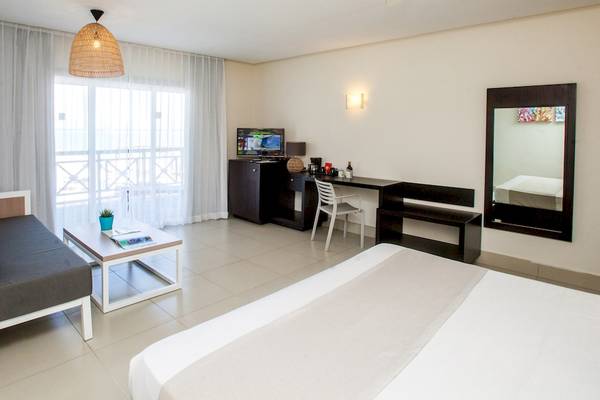 Innenansicht eines Zimmers im Vista Sol Punta Cana Beach Resort mit einem Bett, einem Schreibtisch, einem Fernseher und einem Fenster.