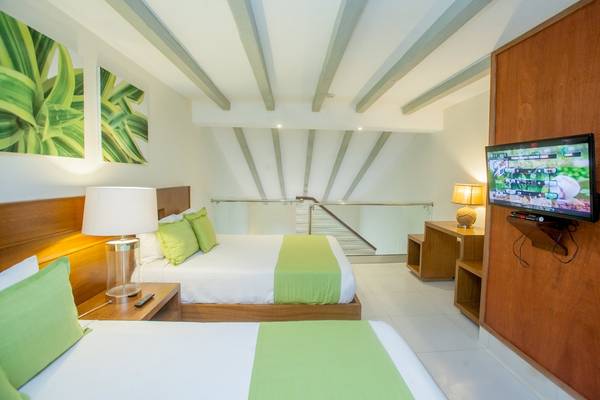 Doppelzimmer im Vista Sol Punta Cana Beach Resort & Spa mit zwei Betten, Fernseher und Lampen.