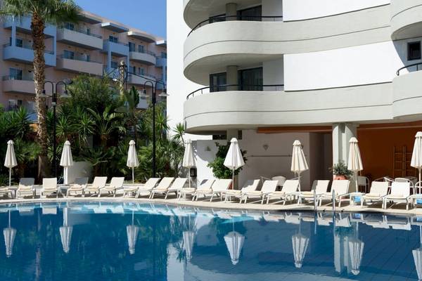 Außenpoolbereich des Aquila Porto Rethymno Hotels mit weißen Liegestühlen und Sonnenschirmen.