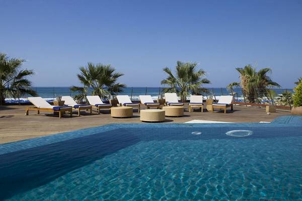 Pool-Lounge-Bereich des Aquila Porto Rethymno Hotels mit Sonnenliegen und Blick auf das Meer.