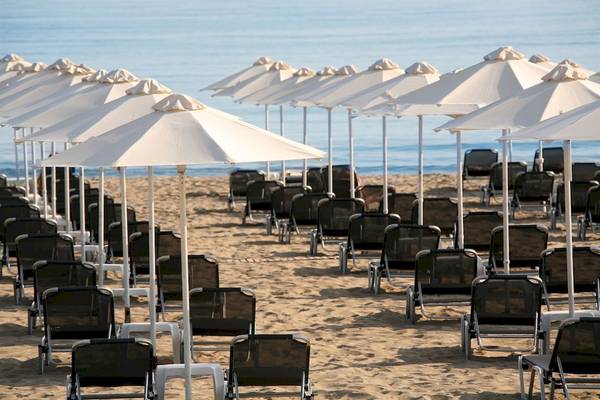 Strand der Aquila Porto Rethymno Hotel mit vielen Sonnenschirmen und Lounge-Stuhle