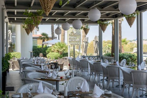 Außenbereich des Aquila Porto Rethymno Hotels mit weißen Stühlen und Tischen.