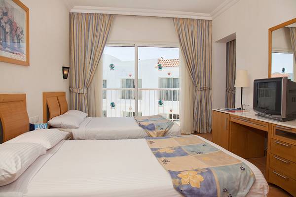 Zwei Betten im Hotelzimmer des Siva Sharm Resort & Spa mit Blick auf ein weißes Gebäude.