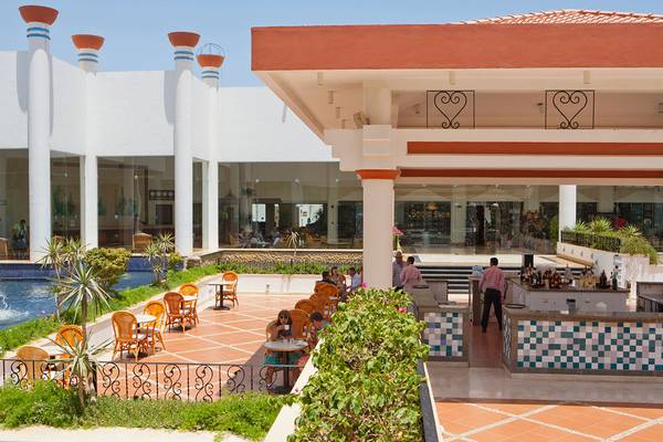 Außenbereich des Siva Sharm Resort & Spa mit Swimmingpool, Tischen und Stühlen.