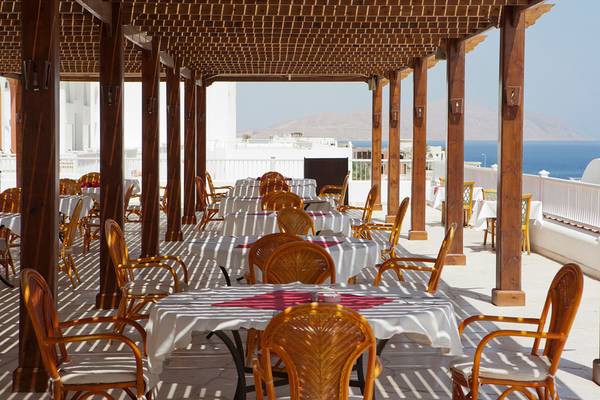 Terrasse des Siva Sharm Resorts mit Tischen und Stühlen, Blick auf das Meer und Berge