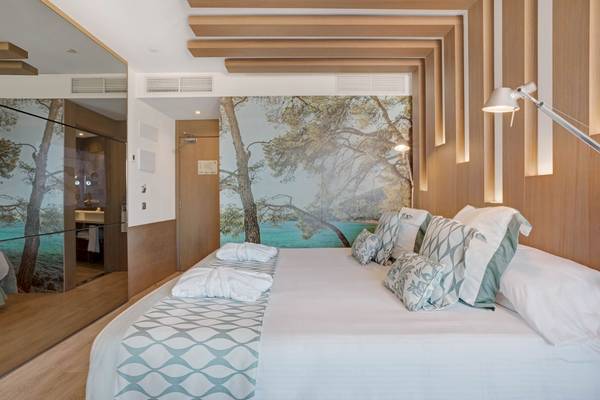 Schlafzimmer im Pure Salt Garonda Hotel mit Bett, Kissen und Panoramawandbild am Meer.