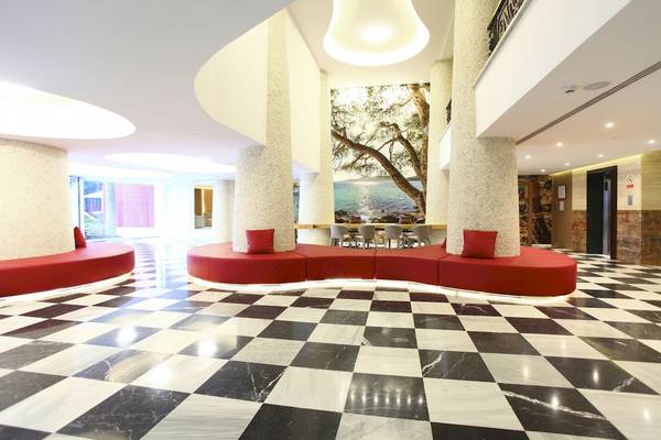 Hotellobby des Pure Salt Garonda mit rotem Sofa und schwarz-weißem Schachbrettboden.