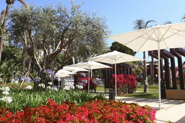 Ein Garten mit bunten Blumen und großen weißen Sonnenschirmen im Hotel Pure Salt Garonda.