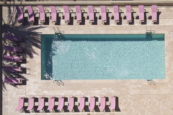 Oberflächenansicht eines Hotelpools mit vielen pinken Liegestühlen.