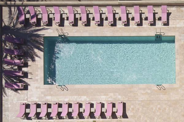 Oberflächenansicht eines Hotelpools mit vielen pinken Liegestühlen.