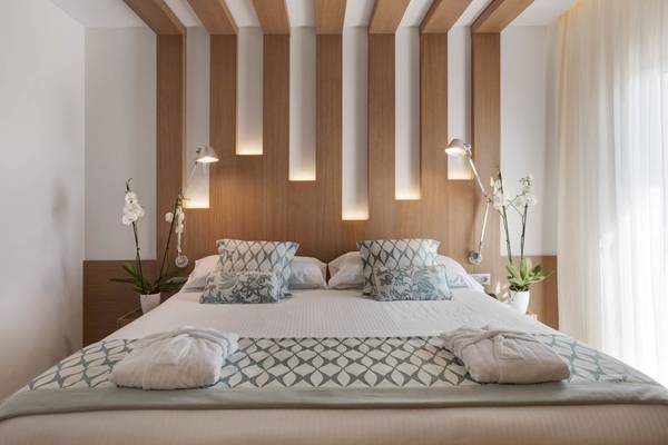 Schlafzimmer im Pure Salt Garonda Hotel mit Bett, Kissen, Nachttischen und Pflanzen.