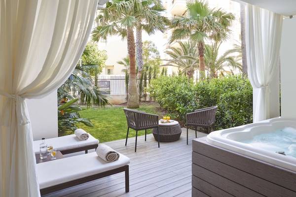 Terrasse des Pure Salt Garonda Hotels mit Whirlpool, Liegen und Tischen im Freien.