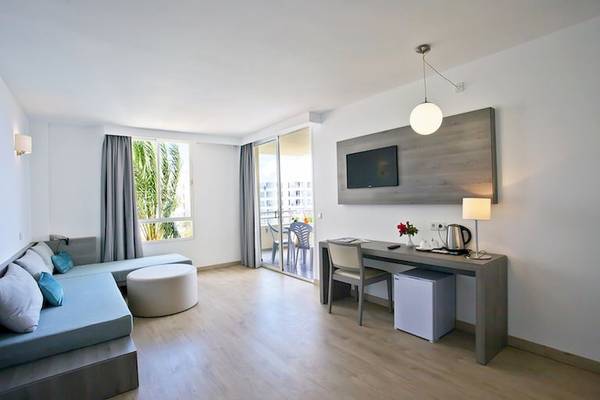 Innenansicht eines Zimmers im Playa Dorada Aparthotel mit Sofa, Schreibtisch und Fernseher.