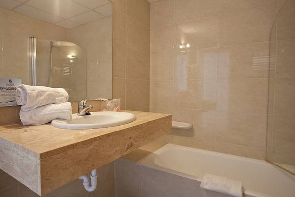 Badezimmer im Playa Dorada Aparthotel mit Badewanne, Waschbecken und Handtüchern.