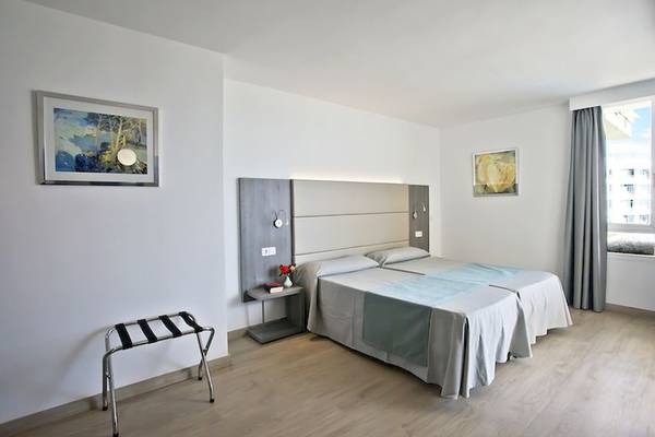 Schlafzimmer im Playa Dorada Aparthotel mit zwei Betten, Nachttischen und Bildern an der Wand.