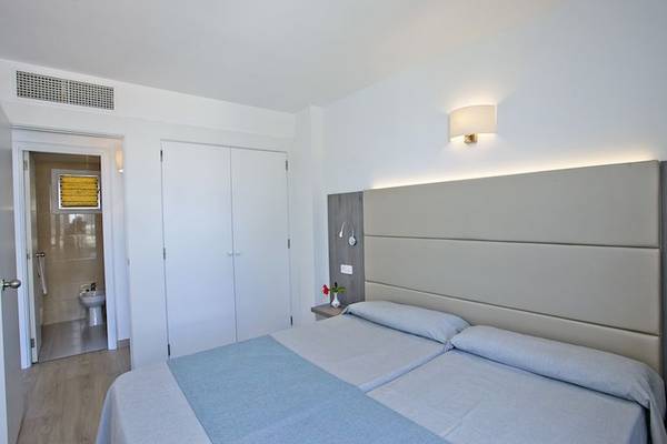 Schlafzimmer im Playa Dorada Aparthotel mit zwei Betten, weißen Wänden und einem Badezimmer.