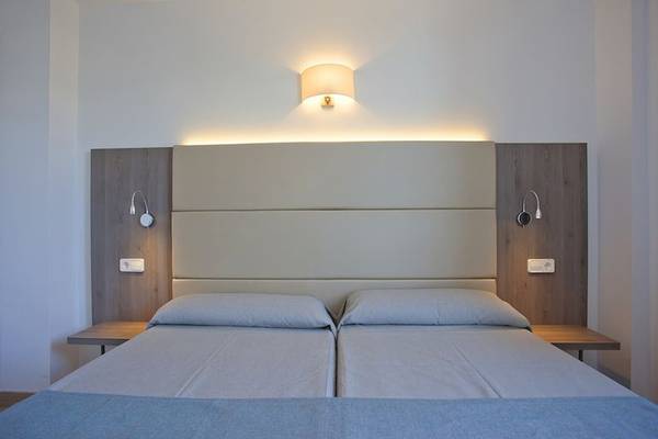 Doppelbett im Schlafzimmer des Playa Dorada Aparthotels mit blauen Laken und weißen Kopfteilen.