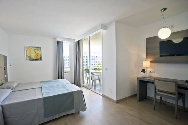 Ein modernes Hotelzimmer im Playa Dorada Aparthotel mit zwei Betten, Schreibtisch, Fernseher und Balkon.