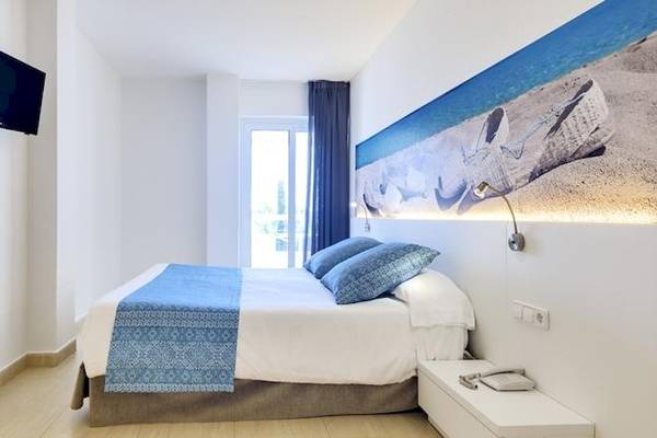 Innenansicht eines Zimmers im Tropic Garden Hotel Apartments mit einem Bett, Fernseher und einem Wandbild.