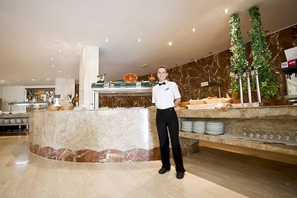 Ein Mitarbeiter im Restaurant des Playa Dorada Aparthotel, das mit Marmor und Holz gestaltet ist.