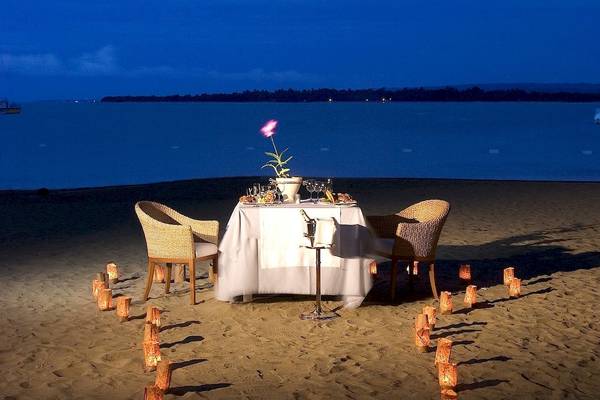 Romantisches Dinner-Setup auf dem Strand des Gran Ventana Beach Resorts mit Kerzen und einer Blumenvase.