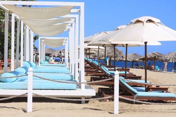 Reihe von Lounge-Sesseln am Strand des Gran Ventana Beach Resorts mit Sonnenschirmen.