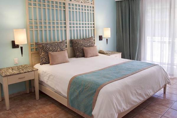 Innenansicht eines Schlafzimmers im Gran Ventana Beach Resort mit einem Bett und zwei Nachttischen.