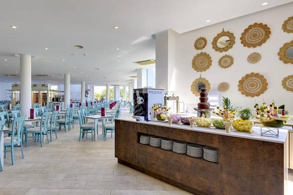 Restaurant des Tropic Garden Hotel Apartments mit blauen Stühlen und Tischen, einer langen Theke mit Obst und einem Schokoladenbrunnen.
