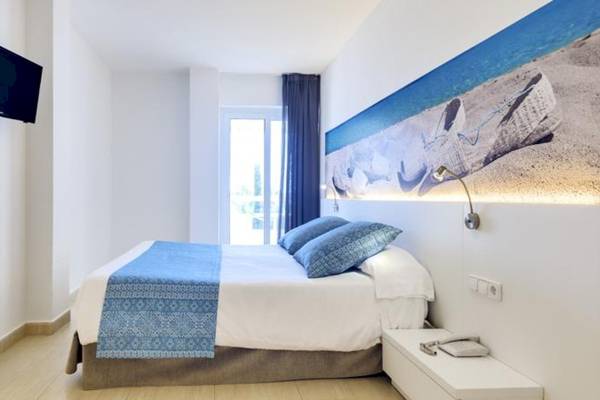 Modernes Hotelzimmer im Tropic Garden Hotel Apartments mit einem Doppelbett, blauen Kissen und einer Wanddekoration.